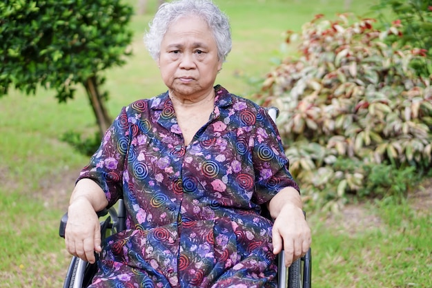 Heller Gesichtspatient des asiatischen älteren oder älteren alten Damenfrauen-Lächelns auf Rollstuhl im Park.