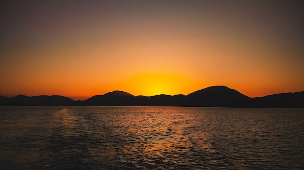 Heller Sonnenuntergang auf dem Hintergrund der Bergansicht vom Meer