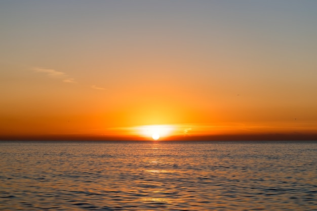Heller Sonnenuntergang mit einer großen gelben Sonne über der Meeresoberfläche