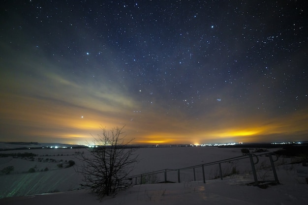 Heller Sternenhimmel über der verschneiten Landschaft im Tal der Hügel