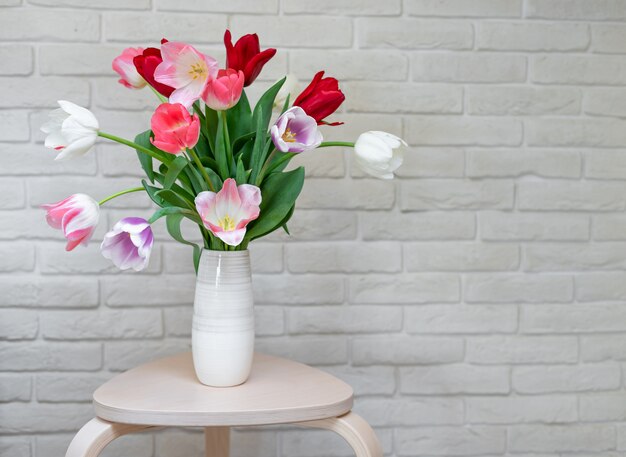 Heller Tulpenstrauß in einer Vase auf einem Holztisch. Grußkarte mit Blumen