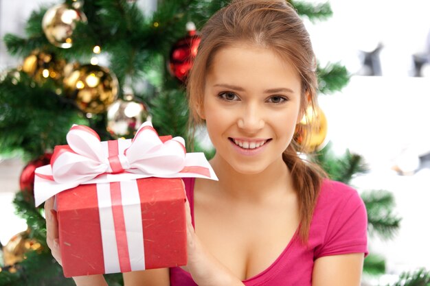 helles Bild einer glücklichen Frau mit Geschenkbox und Weihnachtsbaum