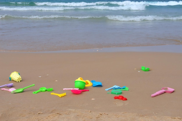 Helles Kinderspielzeug auf dem Sand- und Meereshintergrund