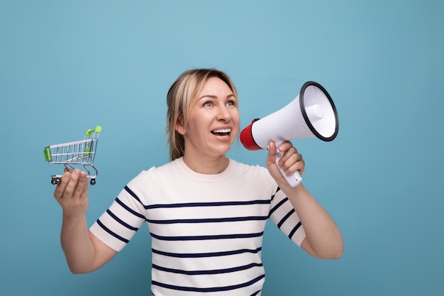 Helles, selbstbewusstes, blondes, attraktives Mädchen in einer Freizeitjacke kündigt über einen Lautsprecher einen Verkauf an