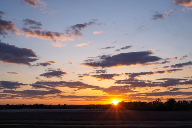 Helles Sonnenlicht am Horizont, letzte Sonnenstrahlen über dem landwirtschaftlichen Feld. Wunderschöner Sonnenuntergang, natürliche ländliche Landschaft