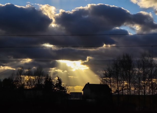 Helles Sonnenlicht durch dunkle Wolken beleuchtet ein Haus im Dorf