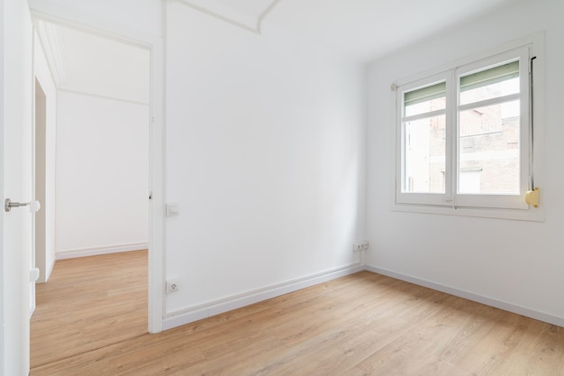 Helles, weißes, geräumiges, unmöbliertes Apartment mit einem Fenster und einem strukturierten Laminatkonzept aus Holz