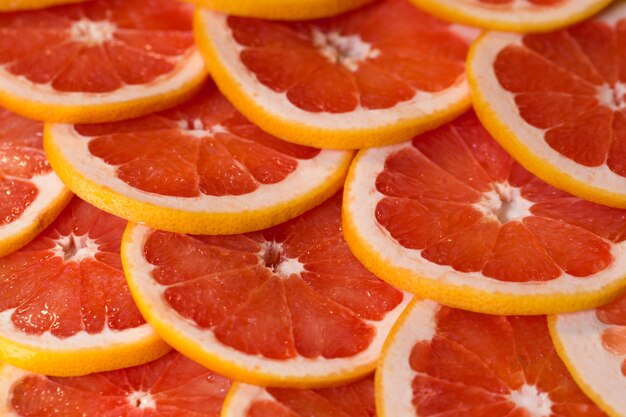 Hellroter Hintergrund mit saftigen Grapefruitscheiben. Gesunder Lebensmittelhintergrund.