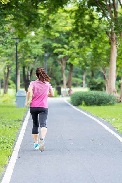 Hembra adulta joven en ropa deportiva corriendo en el parque al aire libre