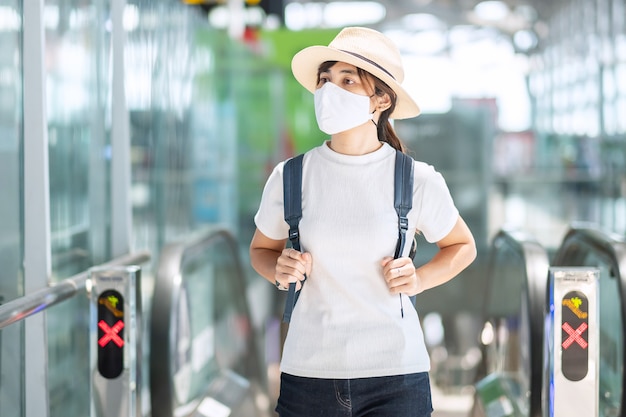 Hembra adulta joven vistiendo mascarilla en la terminal del aeropuerto