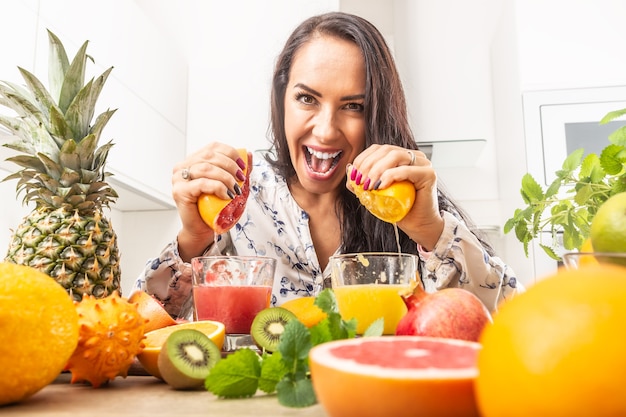 Foto hembra exprimiendo naranja roja y amarilla en un jugo fresco.