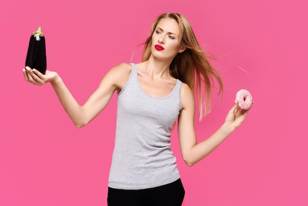 Hembra con un fondo rosa con una hermosa sonrisa sosteniendo y mirando a berenjena y donación