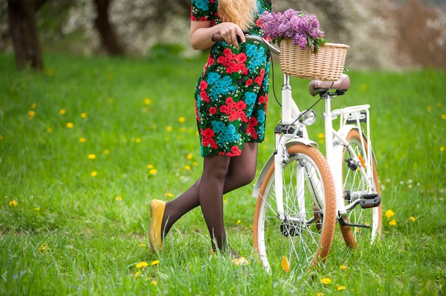 Hembra guarda bicicleta retro blanca con flores lilas.