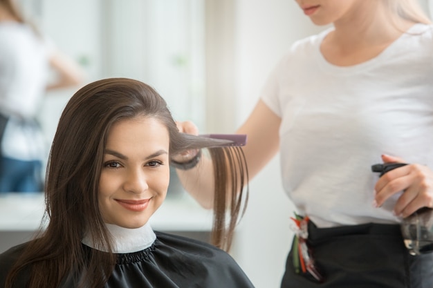 Hembra joven sentada en el cepillo de peinado de peluquería