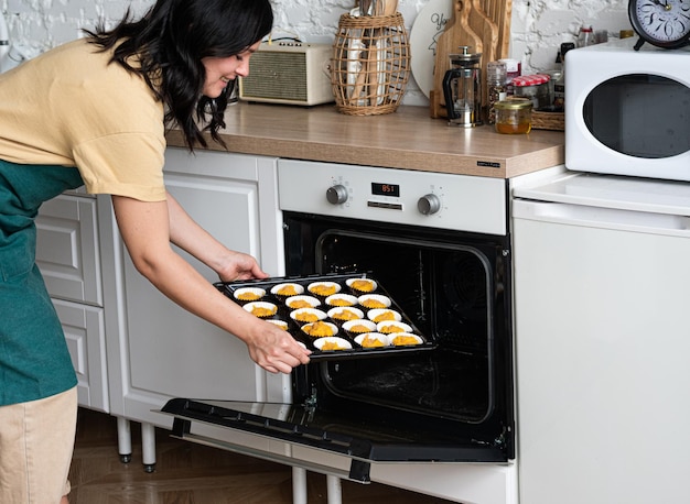 Hembra pone una bandeja con pastelitos en el horno Slow life