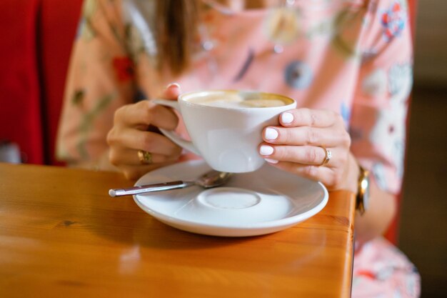 Hembra que sostiene una taza de café en un café