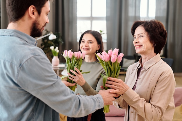 Hembras alegres con tulipanes mirando amable joven