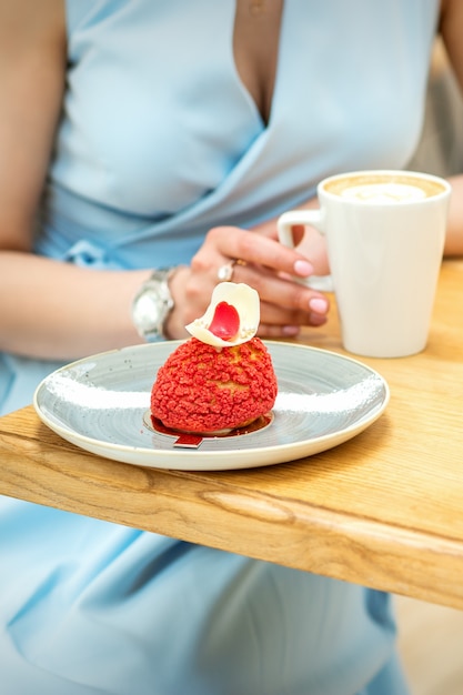 Las hembras jóvenes bebiendo café con un trozo de tarta sentados a la mesa en un café al aire libre