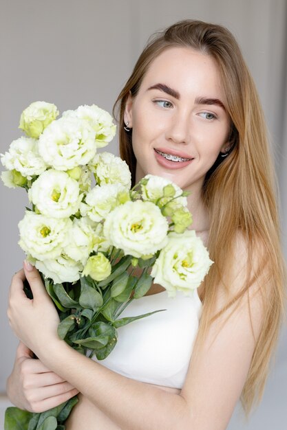 Hemd, hält einen Blumenstrauß und betrachtet die Blumen, den Duft genießend.