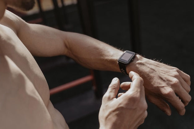 Foto hemdloser athlet, der smartwatch verwendet, während er sich ausruht. fitness-gadgets-konzept. platz für text. platz kopieren