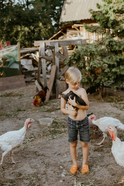 Foto hemdloser junge hält ein huhn auf der farm