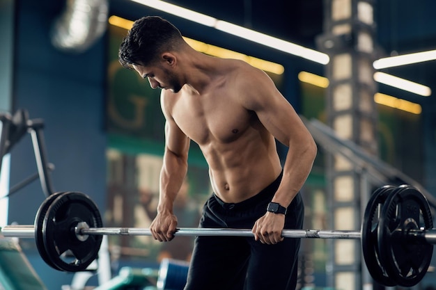 Hemdloser muskulöser arabischer Mann, der beim Training im Fitnessstudio schwere Hanteln hebt