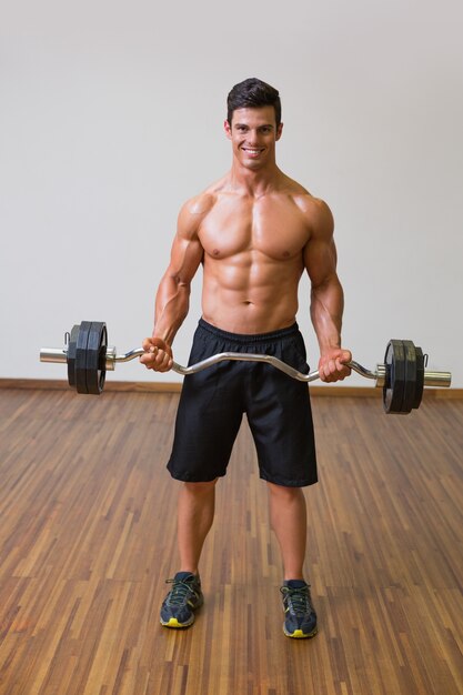 Hemdloser muskulöser Mann, der Barbell in der Turnhalle anhebt