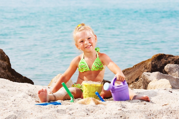 Heppy Niña jugando en la playa con balde y pala