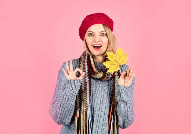 Herbst. Überraschte Frau mit Ahornblatt. Lächelnde Frau mit Herbstblatt zeigt Zeichen ok. Gelbes Ahornblatt. Sexy Frau hält Blatt und zeigt Zeichen ok. Isoliert. Herbststimmung. Herbstblätter. Unterschreiben in Ordnung.