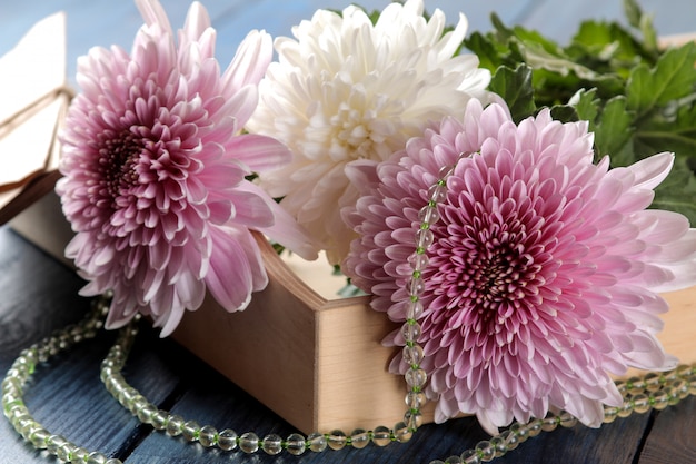 Foto herbst chrysanthemenblumen mit perlen und buchstaben auf einem dunkelblauen tisch
