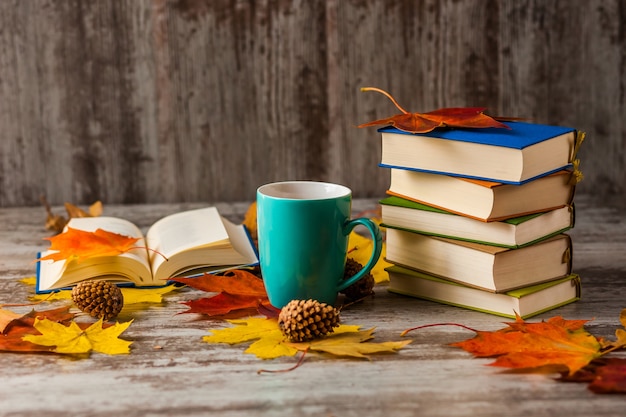 Herbst. Ein offenes Buch. Tasse Tee, Kaffee, Kakao. Gelbrote Blätter. Holzoberfläche