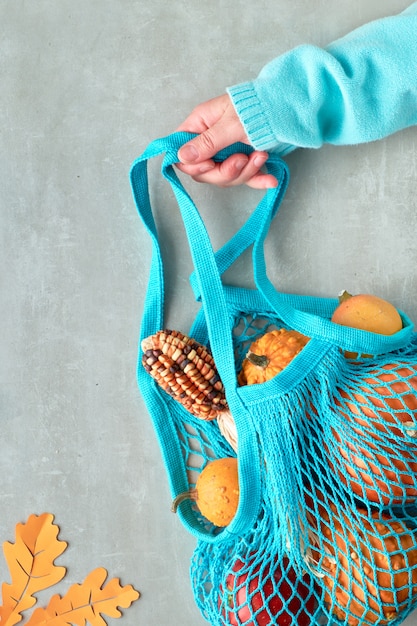 Herbst flach lag mit türkisfarbener Saitentasche mit orangefarbenen Kürbissen, oben auf grauem Stein