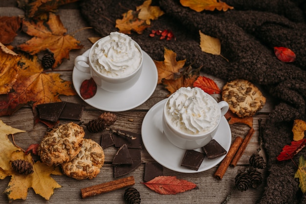 Herbst, Herbstlaub, heiße dampfende Tasse Kaffee und ein warmer Schal auf Holztisch.