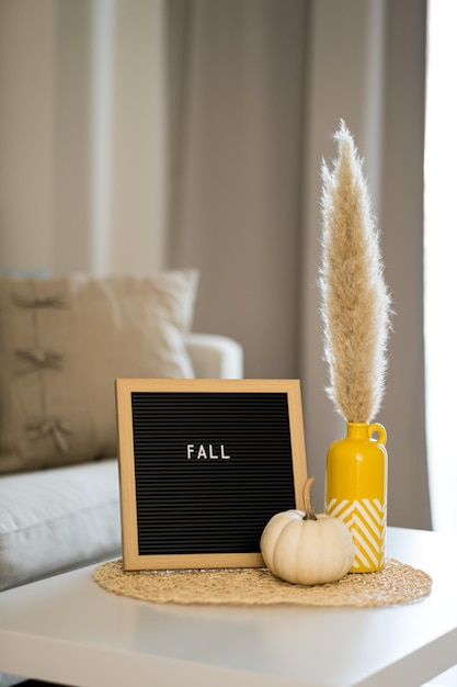 Herbst home interior Zusammensetzung Wort fallen auf Tafel weißer Kürbis Gemütliches DekorationskonzeptHalloween-Urlaubsatmosphäre