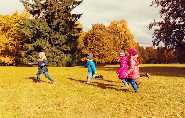 herbst, kindheit, freizeit und personenkonzept - gruppe glücklicher kleiner kinder, die tagspiel spielen und draußen im park laufen