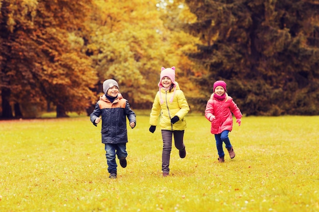 herbst, kindheit, freizeit und personenkonzept - gruppe glücklicher kleiner kinder, die tagspiel spielen und draußen im park laufen