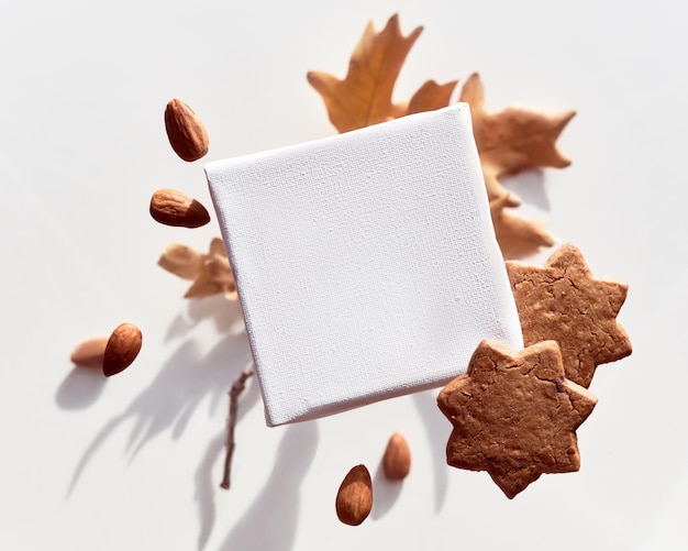 Herbst leere Leinwand Mockup mit Copyspace Fliegende, schwebende Sternkekse und Mandeln Gruppe von leckeren Snacks und trockenen Herbsteichenblättern auf weißem Hintergrund