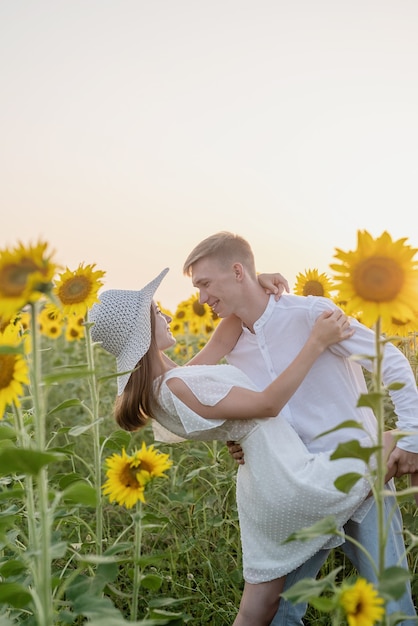 Herbst Natur. Junges romantisches Paar, das bei Sonnenuntergang im Sonnenblumenfeld geht