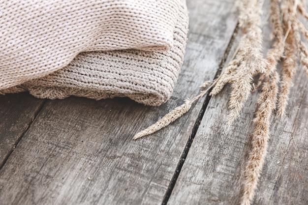 Foto herbst- oder winterhintergrund. stapel gemütlicher strickpullover aus wolle auf holztisch