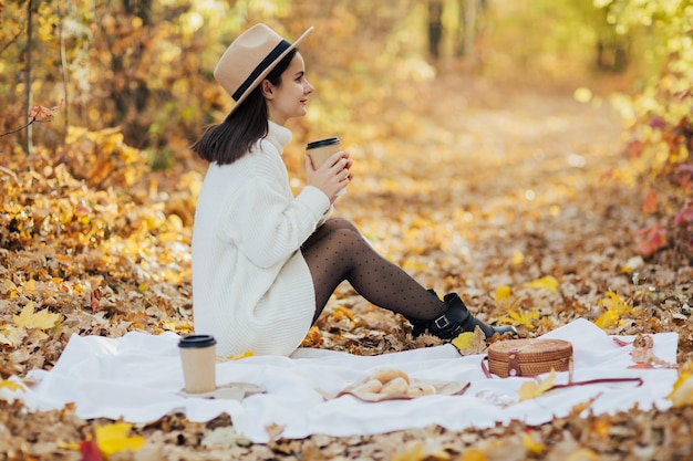 Herbst-Picknick im Park Mädchen, das ein gemütliches Picknick genießt