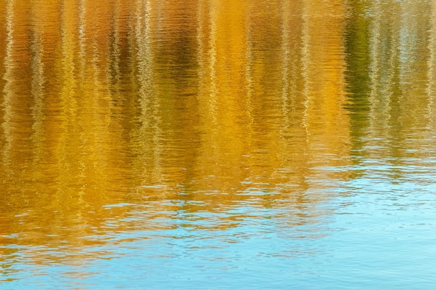 Herbst unscharfer Hintergrund von reflektierten gelben Bäumen im Flusswasser