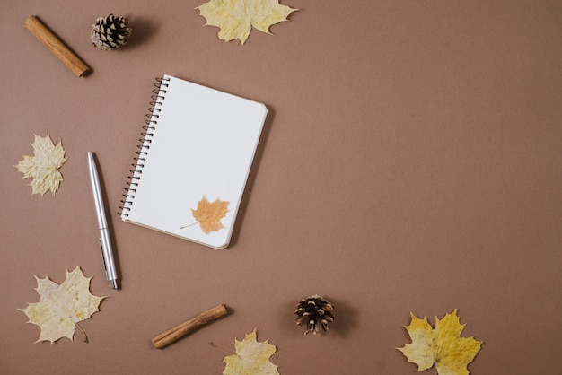 Herbst Zusammensetzung. Goldene Ahornblätter, Stöße, Notizbuch und Stift auf braunem Hintergrund.