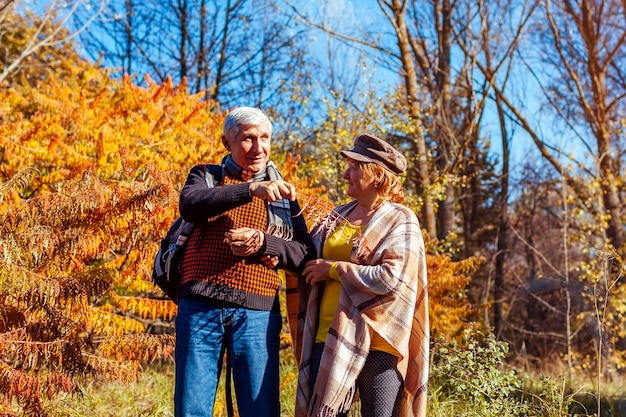 Foto herbstaktivitäten seniorenpaar spazieren im herbstpark mann und frau genießen die natur und reden