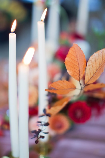 Herbstblumen, trockene Blätter und brennende Kerzen Schönes, gemütliches Tischgedeck Herbst-Dinner-Konzept