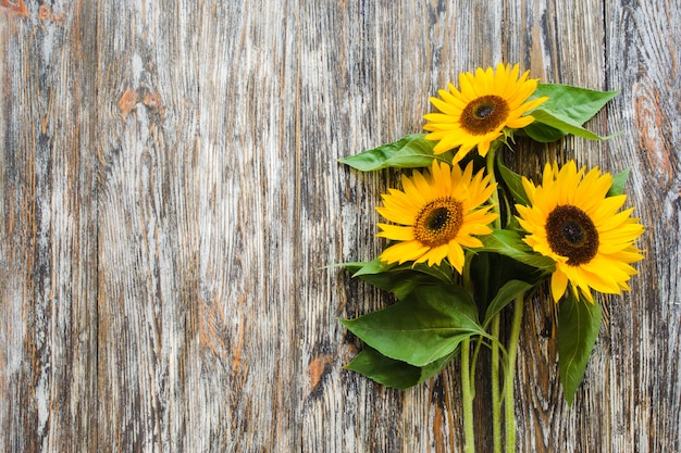 Herbstblumenstrauß von gelben Sonnenblumen auf Weinlese maserte Holztisch.