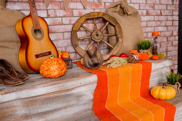 Herbstdekor mit roggen, weizen, mit gelben ahornblättern, kürbisen, roten äpfeln gealtertes holz. saisonale angebote und urlaub postkarte. herbstliche dekoration.