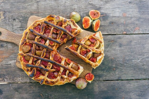 Herbstfeigenkuchen oder -törtchen mit Zimt auf einem alten Holztisch. Ansicht von oben