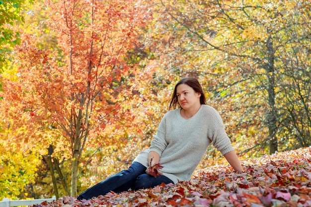 Herbstfrau auf Blatthintergrund Schöne Frau im Herbst-Park