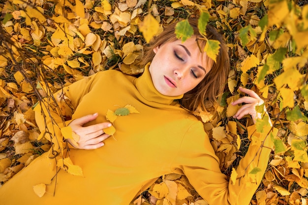 Herbstfrau liegt auf gelbem Herbstlaub