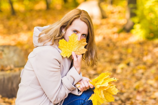 Herbstfrau und gelber Ahorngartenhintergrund des Herbstes